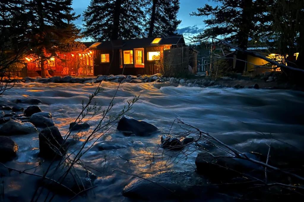 une maison la nuit avec de la neige devant elle dans l'établissement Thorpe On The Water. Creekside Nederland Cabin., à Nederland