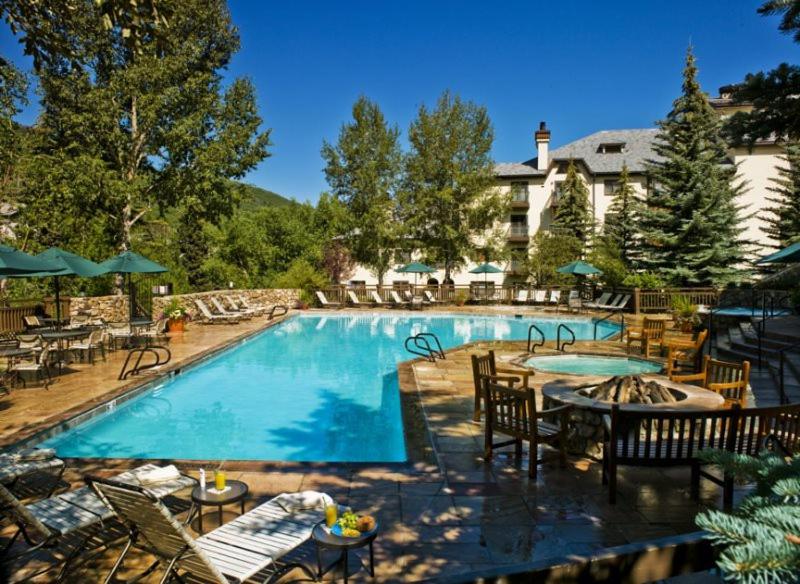 una gran piscina con mesas y sillas junto a un hotel en The Charter 2 Bedroom Ski In, Ski Out Vacation Rental With Hot Tub Access And Easy Walk To Village en Beaver Creek
