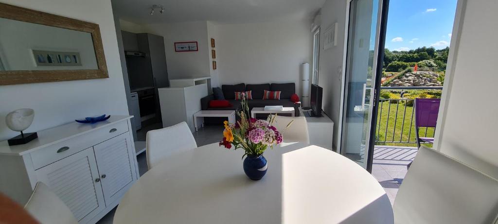 eine weiße Küche mit einer Blumenvase auf dem Tisch in der Unterkunft Appartement devant la plage avec piscine in Concarneau