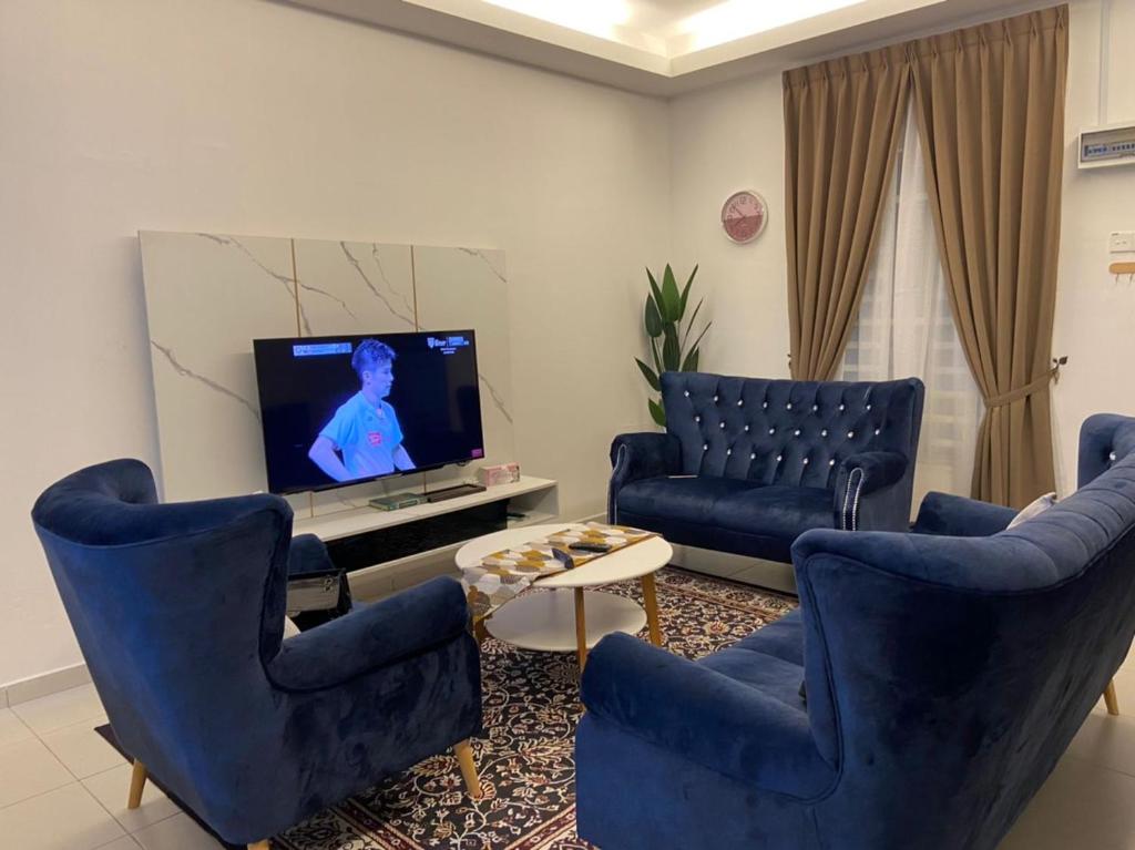 uma sala de estar com cadeiras azuis e uma televisão em Rosnah Homestay em Kampong Ayer Resam