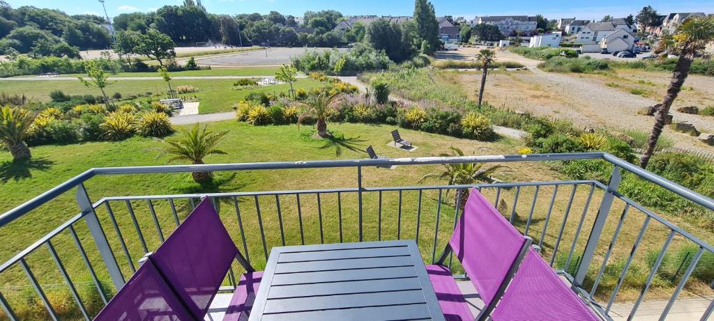 a chair on a balcony with a view of a park at Appartement devant la plage avec piscine in Concarneau