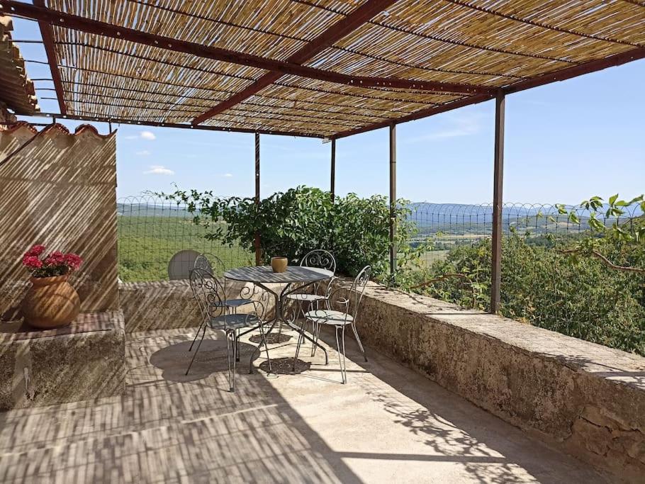 a patio with a table and chairs under a roof at Gite avec piscine "La maison de Valentine" en Provence in Le Plan