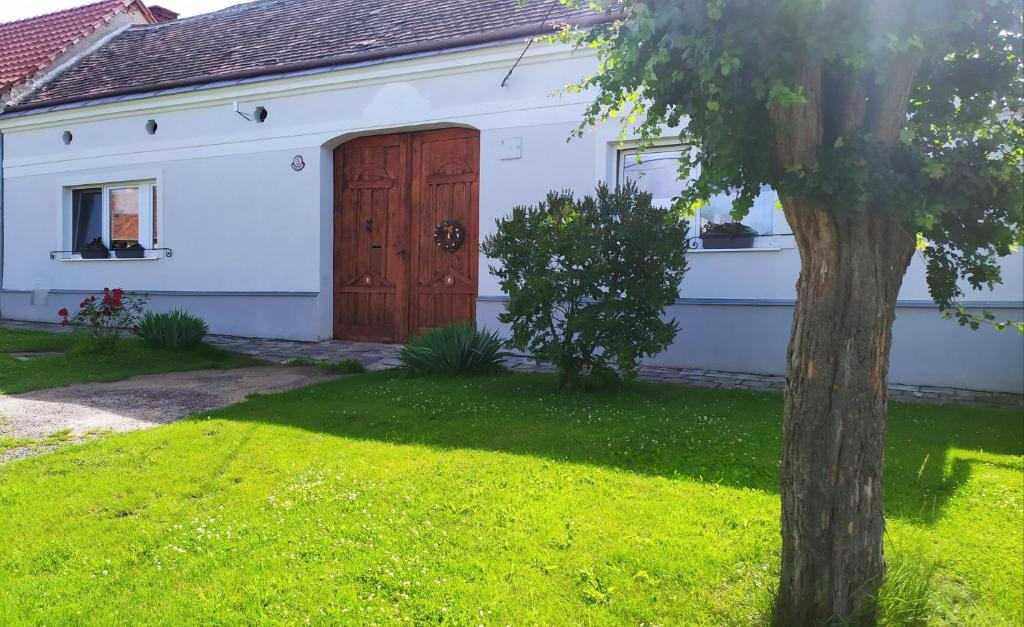 ein weißes Haus mit einer Holztür und einem Baum in der Unterkunft Apartmán Na pětce in Znojmo