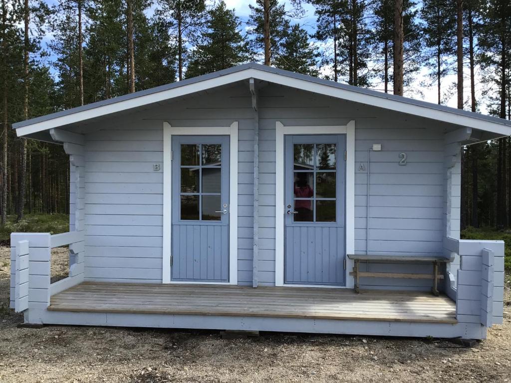 een kleine witte schuur met een veranda en een deur bij Koli caravan cottages in Kolinkylä