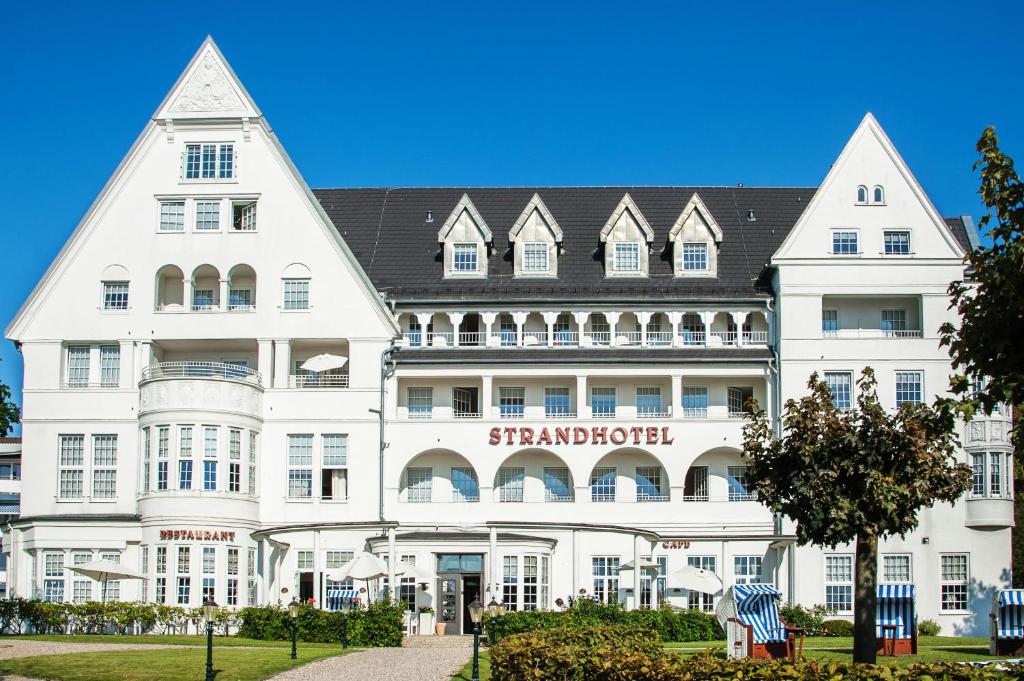 a large white building with a sign on it at Strandhotel Glücksburg in Glücksburg