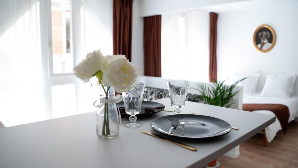 uma mesa com dois pratos e um vaso com flores brancas em LITTLE MAMA 80 meters from public parking Rapp em Colmar