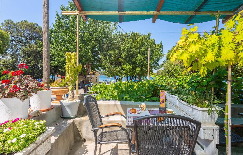 un patio con mesa, sillas y flores en Stunning Apartment In Punat With Wifi, en Punat