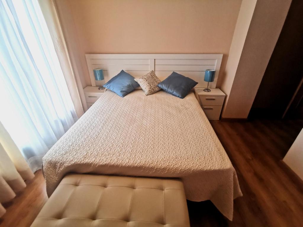 um quarto com uma cama grande e almofadas azuis em Riaza Vacacional - Apartamento en el centro em Riaza