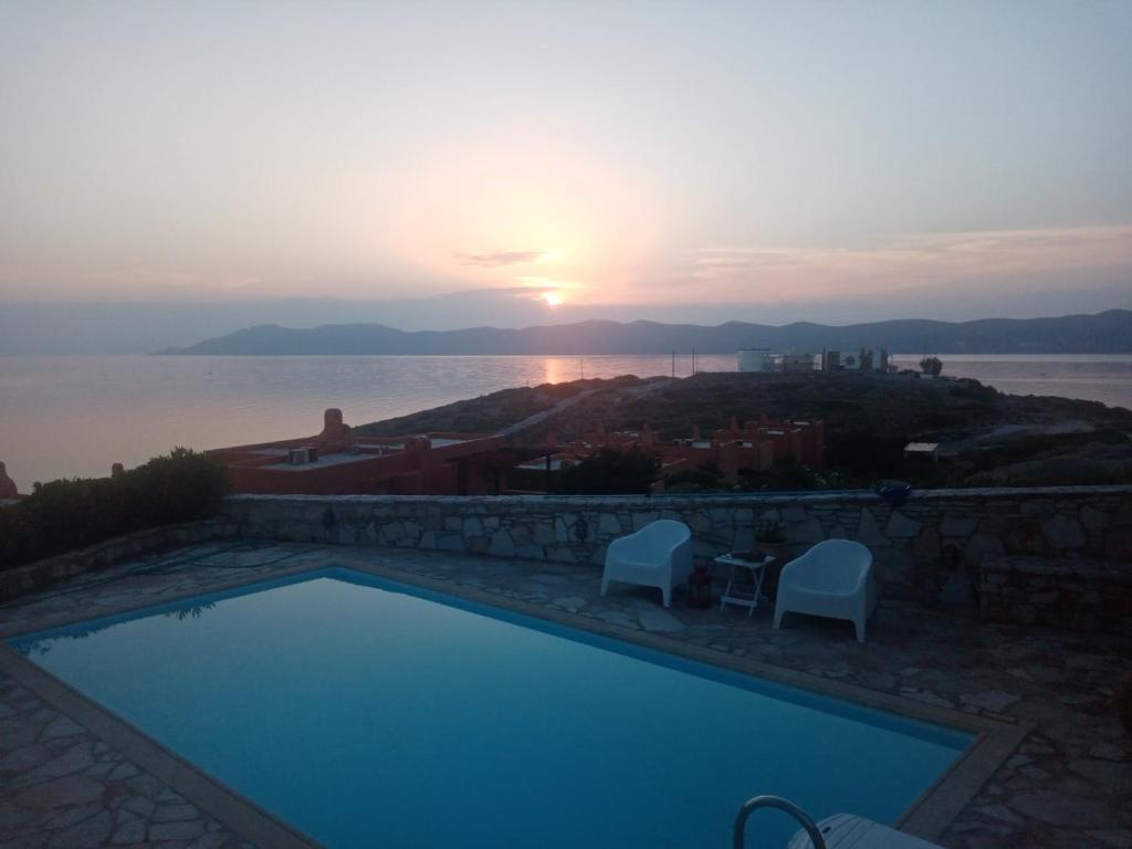 una piscina con puesta de sol sobre el agua en Big Blue Villa, en Sounio