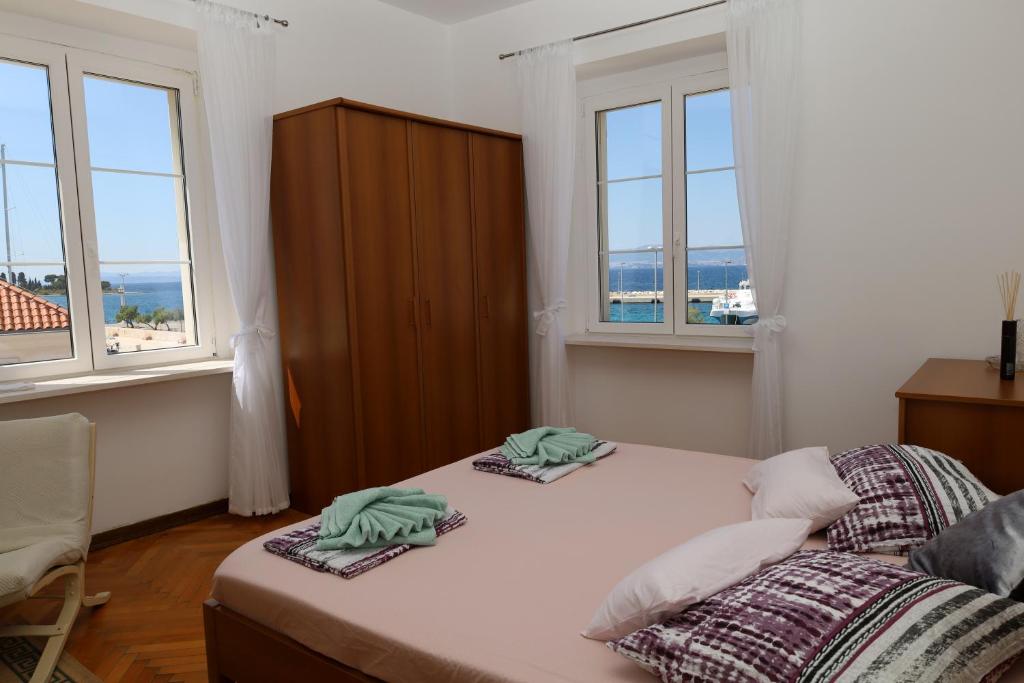 ein Schlafzimmer mit zwei Handtüchern auf einem Bett mit Fenstern in der Unterkunft Apartman DAJANA in Supetar