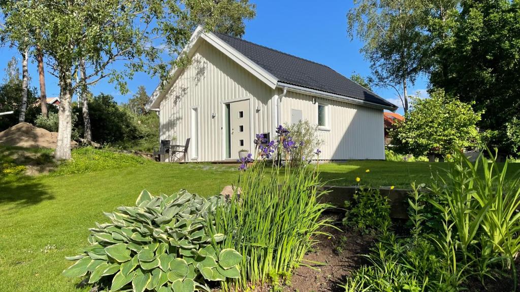 een witte schuur met een tuin ervoor bij Floda, Minihus på 62m2 för plats för 4 vuxna och 2 barn in Floda