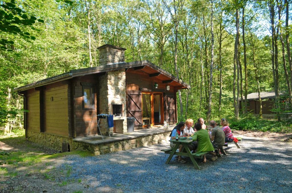 un grupo de personas sentadas frente a una pequeña cabaña en Village de Vacances d'Oignies en Oignies