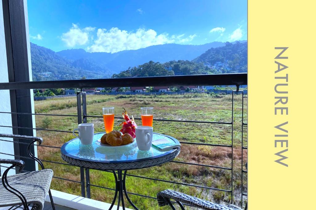 a table on a balcony with two glasses of orange juice at Tranquil Condo close to Beach in Kamala Beach
