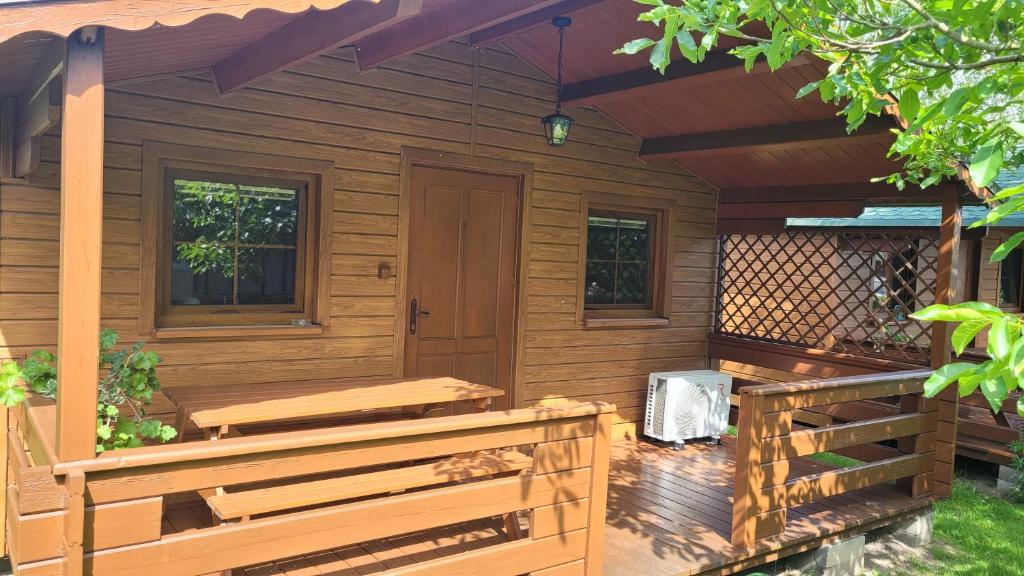 a wooden cabin with a porch and benches at Jaskolcze Gniazdo in Dziwnówek