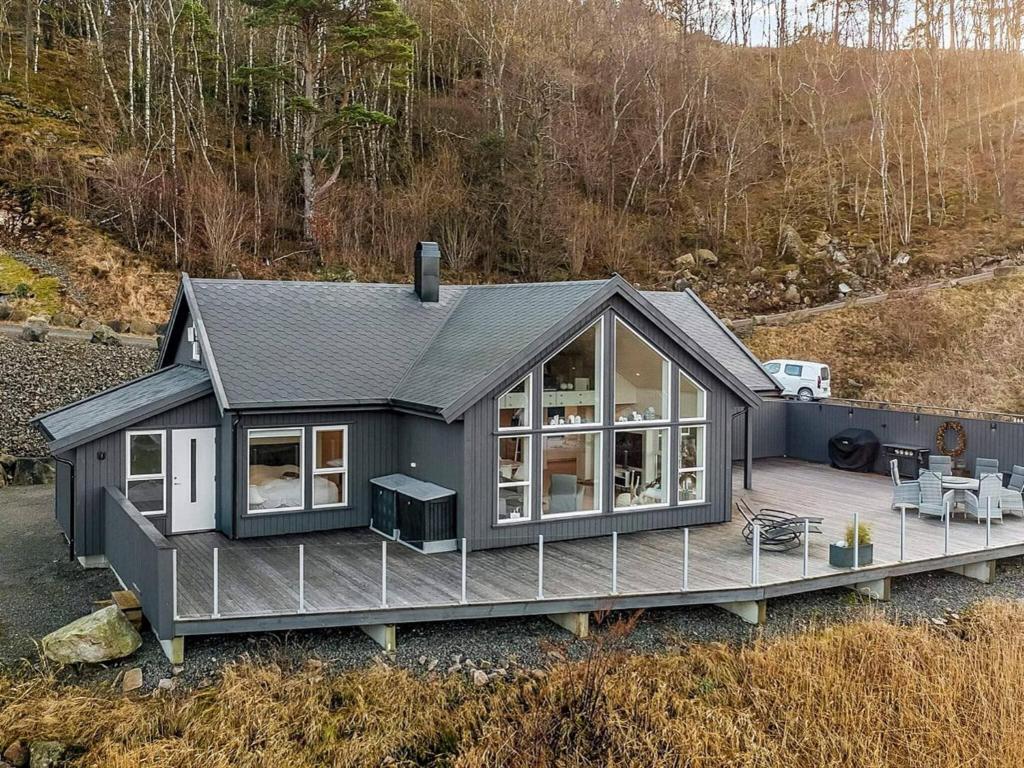 a small grey house with a deck in a field at 8 person holiday home in Lyngdal in Lyngdal