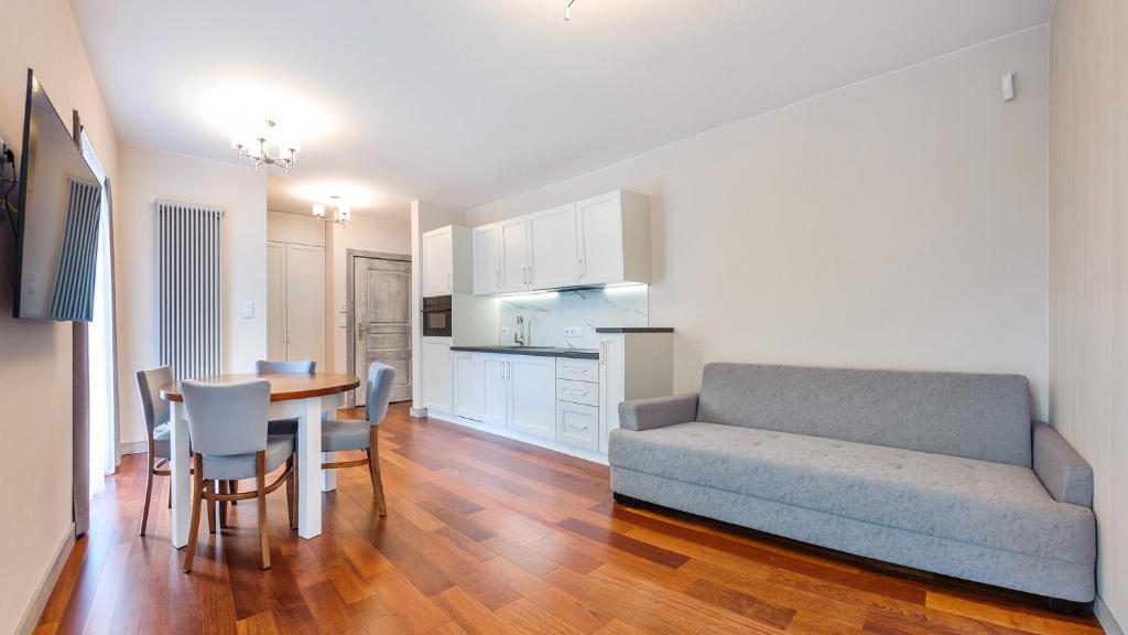 salon z kanapą i stołem oraz kuchnia w obiekcie Apartamenty Sopockie Błonie w mieście Sopot