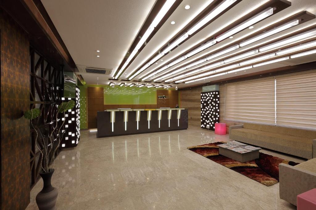 a lobby with a waiting room with a couch and tables at HOTEL THE LOTUS PARK in Ahmedabad