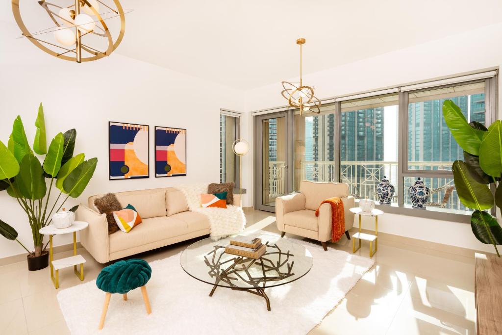 Una sala de estar con un sofá y sillas y ventanas. en Prime Retreats - 29 Emaar Boulevard Downtown Dubai, en Dubái