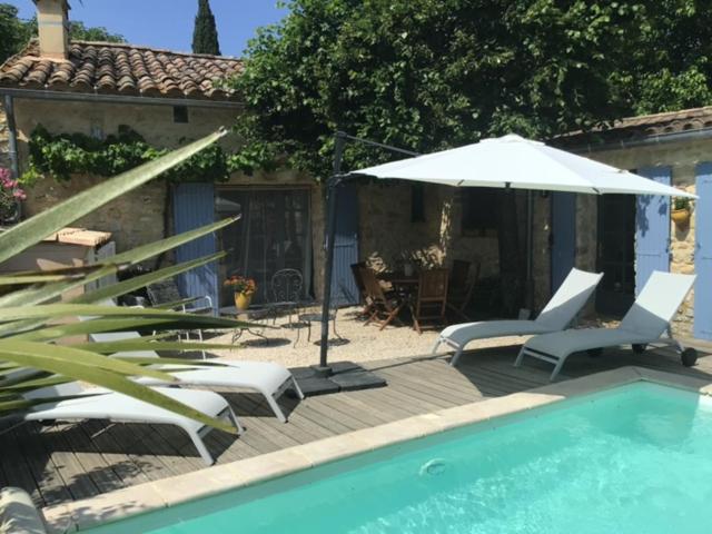 um pátio com cadeiras, um guarda-sol e uma piscina em Maison de plain pied pour 4 pers piscine Lussan em Lussan