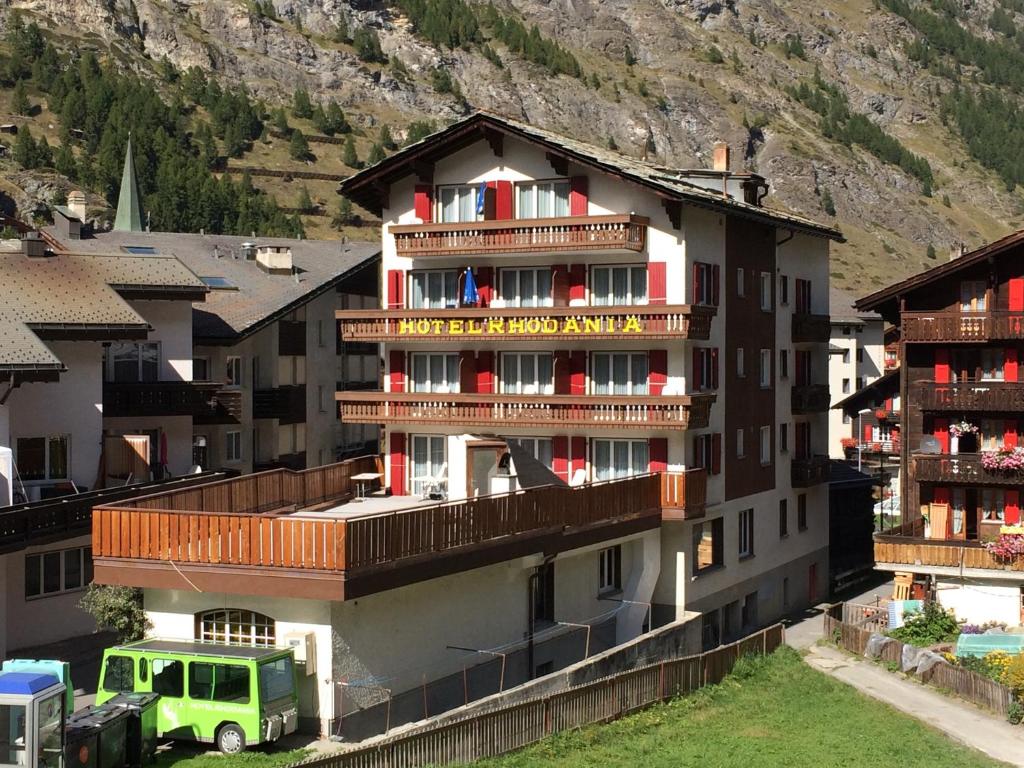 a building with a green truck parked in front of it at Hotel Rhodania in Zermatt