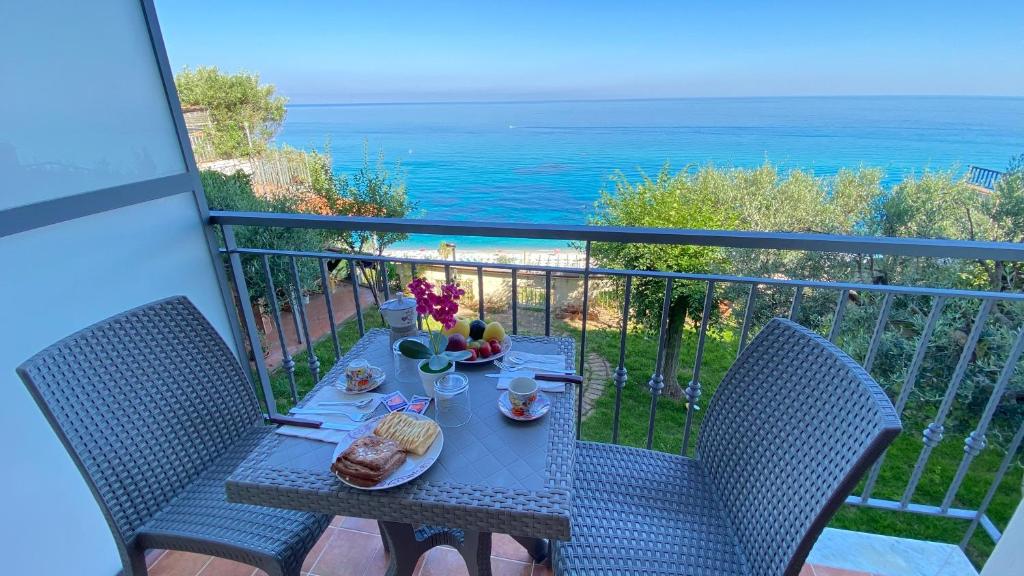 una mesa y sillas en un balcón con vistas al océano en Caia Appartamenti Tropea, en Tropea