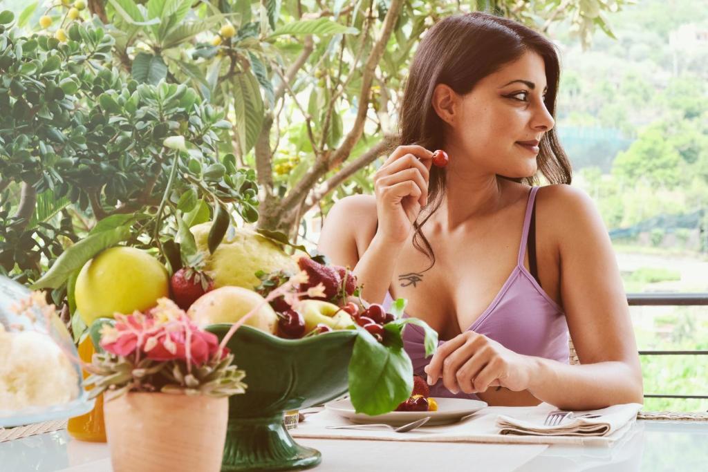 una mujer sentada en una mesa con un tazón de fruta en B&B Maria Grazia, en Vico Equense