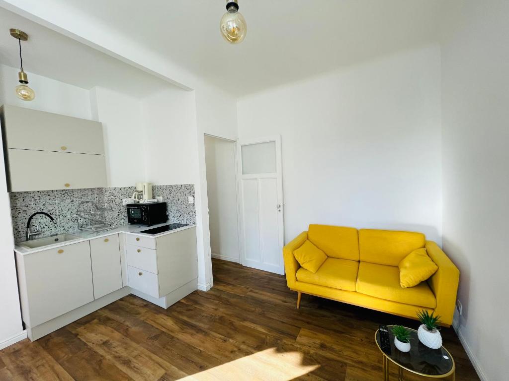 a living room with a yellow couch and a kitchen at Appartement Bonaparte centre ville d&#39;Ajaccio in Ajaccio