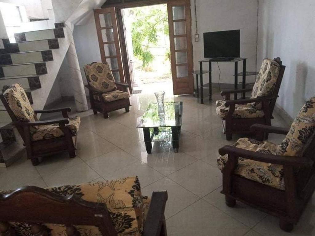 sala de estar con sillas, TV y mesa en TAMATAVE Chez Bien Aimée, en Toamasina