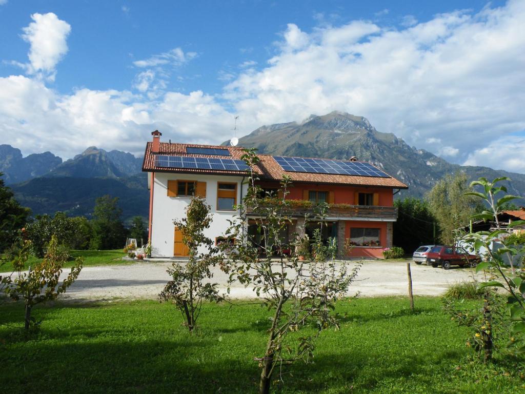 une maison avec des panneaux solaires sur le toit et des montagnes dans l'établissement Agriturismo Al Bachero, à Belluno