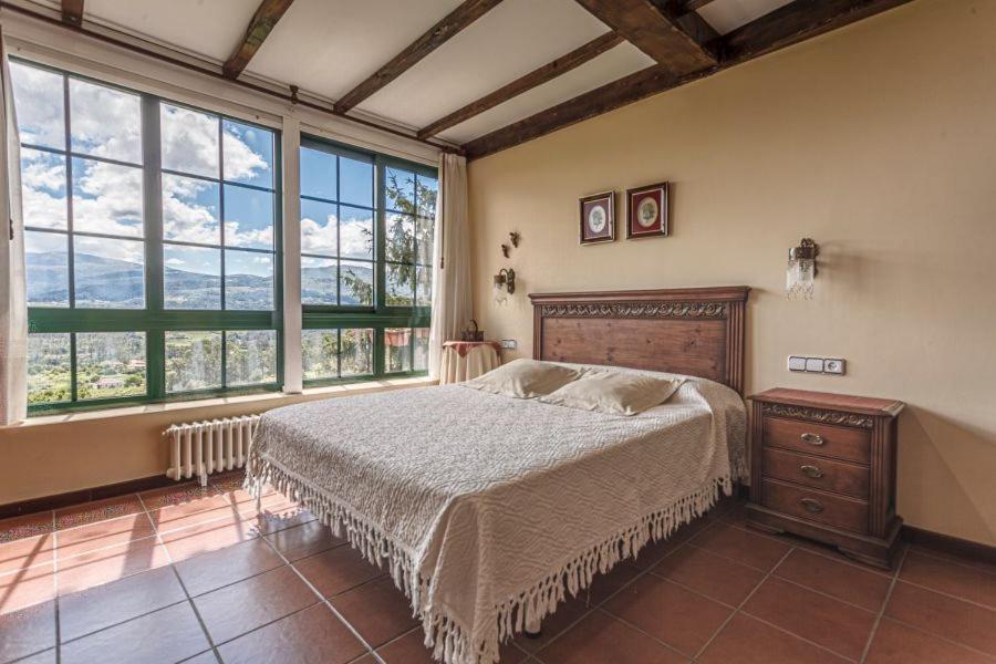 a bedroom with a large bed and large windows at CASA PAZOS-ARBO in Arbo