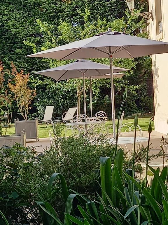twee parasols naast een tafel en stoelen bij Le Petit Matin in Bayeux