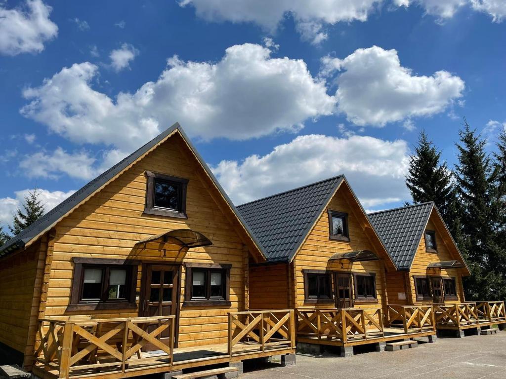 a log cabin with a blue sky and clouds at Domek Sudecki Karłów in Karłów