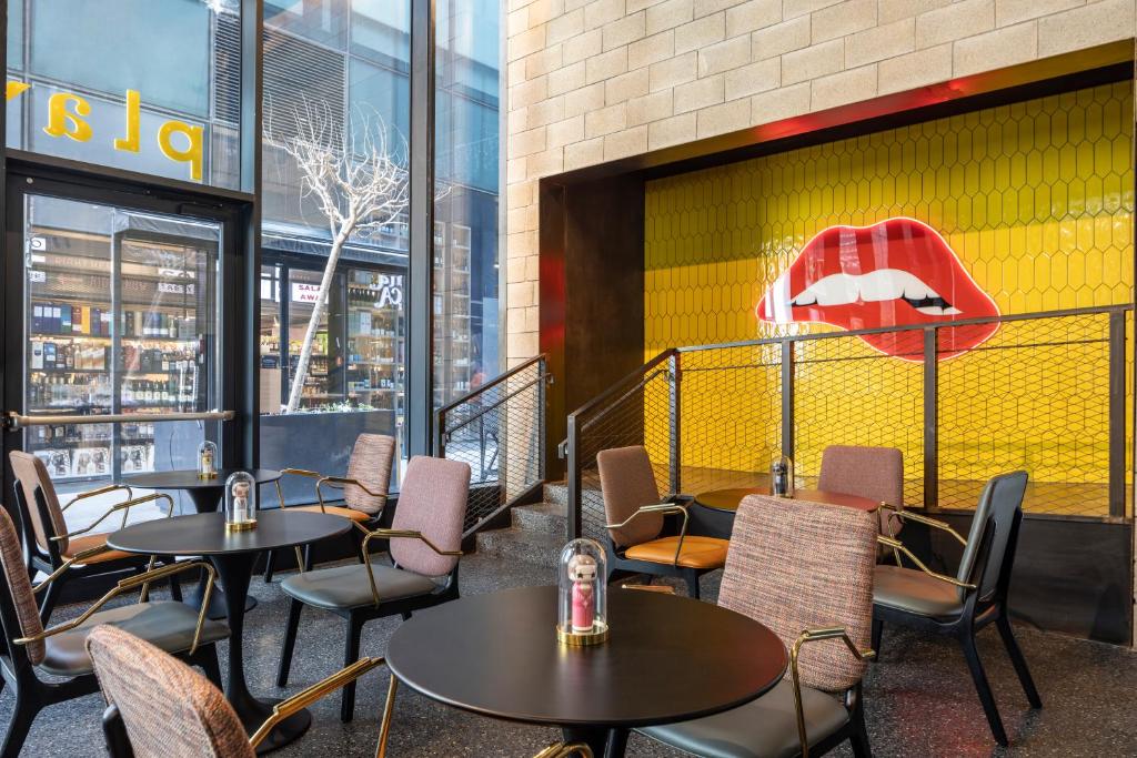 a restaurant with tables and chairs in front of a yellow wall at Play Midtown Hotel Tel Aviv in Tel Aviv