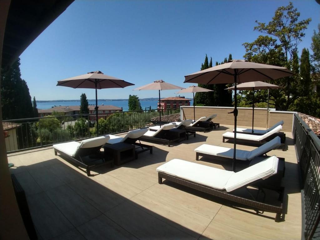 un grupo de tumbonas y sombrillas en una terraza en Hotel Meridiana, en Sirmione