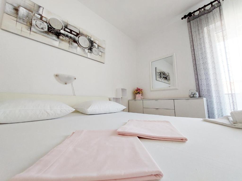 a white bedroom with a white bed with two pillows at APARTMENT ELI in Pag