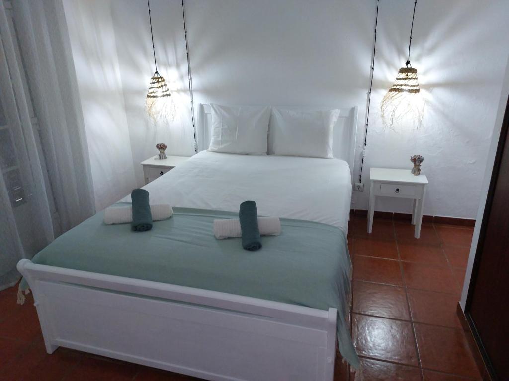 um quarto com uma cama branca e 2 almofadas em Gota D'agua Guest House em Vila Nova de Milfontes