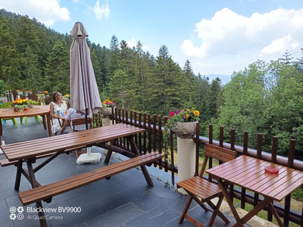 een vrouw aan een tafel op een dek met een paraplu bij Chambre La Lavandula Col de Turini 