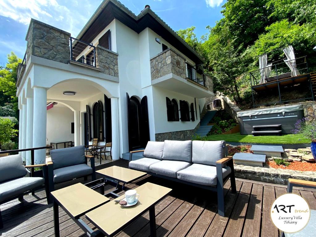 a patio with couches and tables in front of a house at ARTtrend Luxury Villa in Tihany