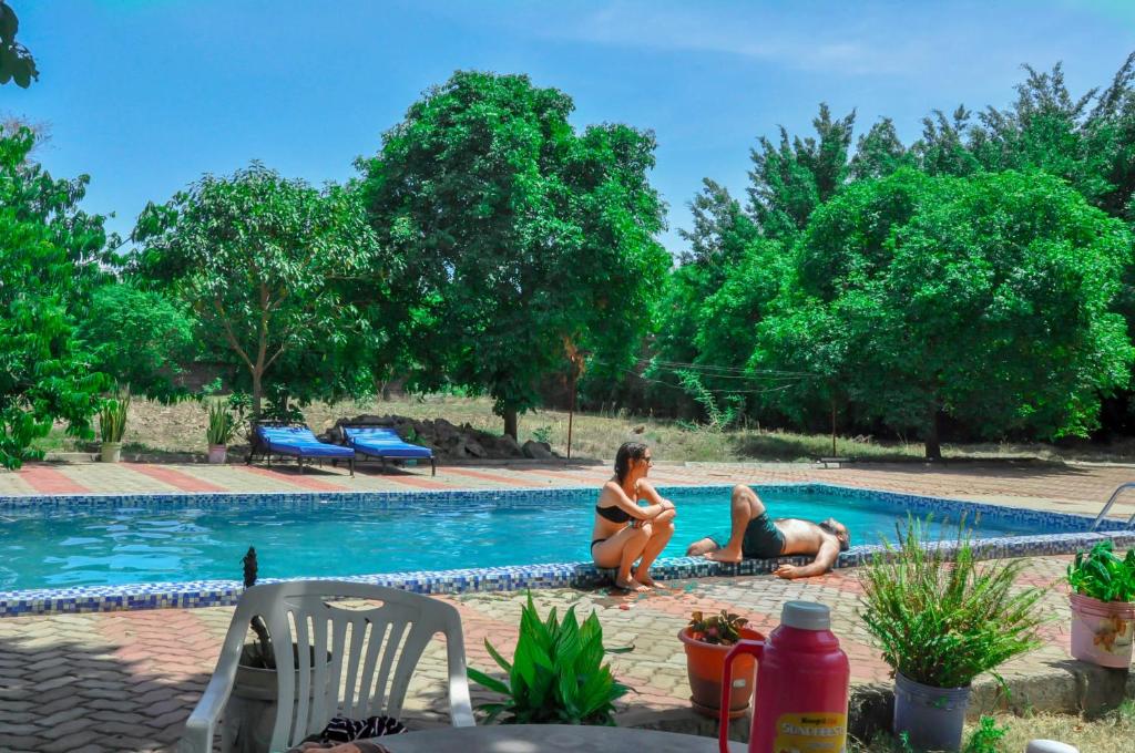 dos mujeres sentadas junto a una piscina en B-MORE COMFORT STAY en Boma la Ngombe