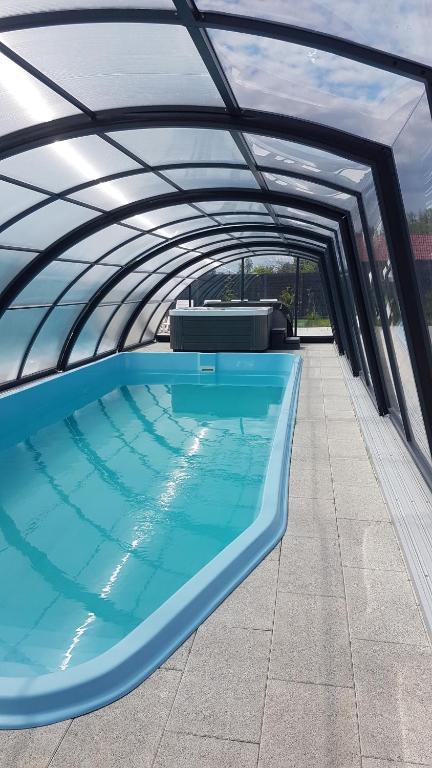 a large swimming pool with a canopy over it at Osada Wypoczynku Jantar Resort&Spa - Luksusowe Domki z Basenem, Sauną i Jacuzzi in Jantar