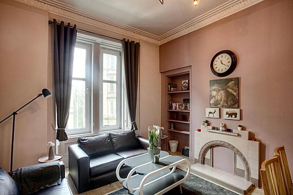 a living room with a couch and a clock on the wall at Stylish Luxury 2-Bed Serviced Apartment in Heart of West End SSE Hydro Botanic Gardens in Glasgow