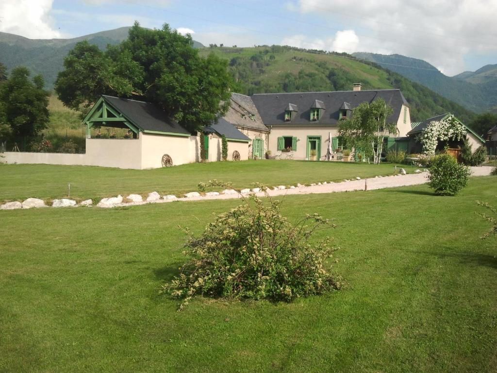 una casa grande en un campo con un patio verde en grange rénovée en gîte/maison/chalet, en Arreau