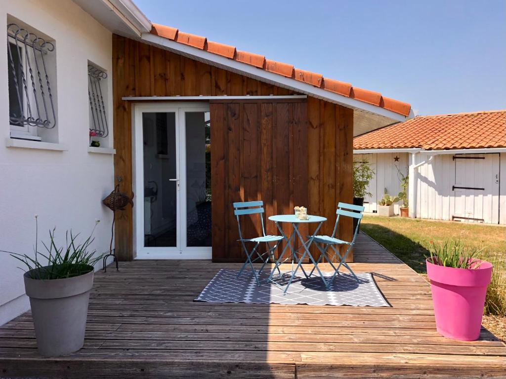 drewniany taras z 2 krzesłami i stołem na nim w obiekcie Logement indépendant Bassin d'Arcachon w mieście Le Teich