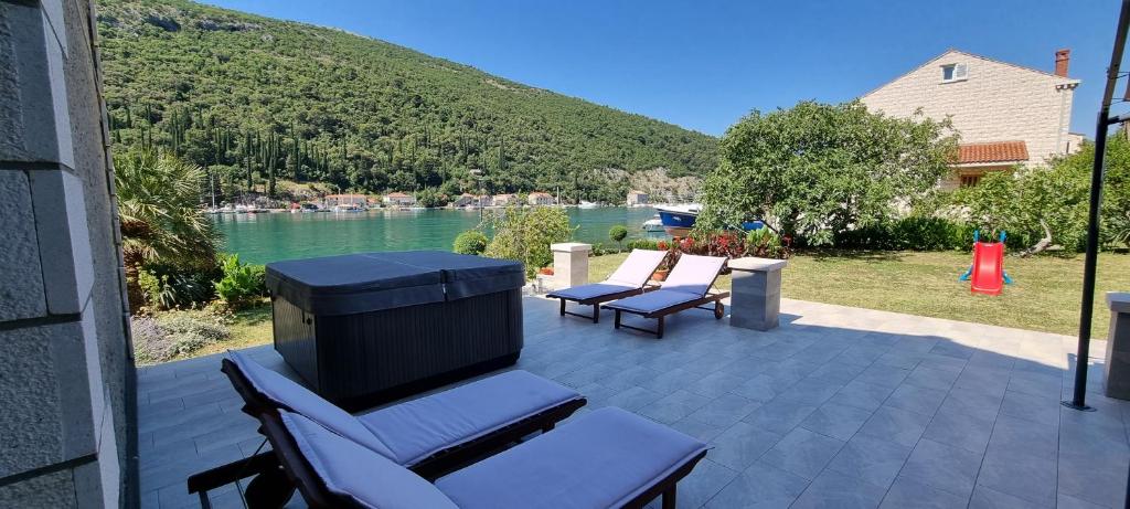 eine Terrasse mit zwei Stühlen, einem Grill und einem See in der Unterkunft Apartment Ombla in Mokošica