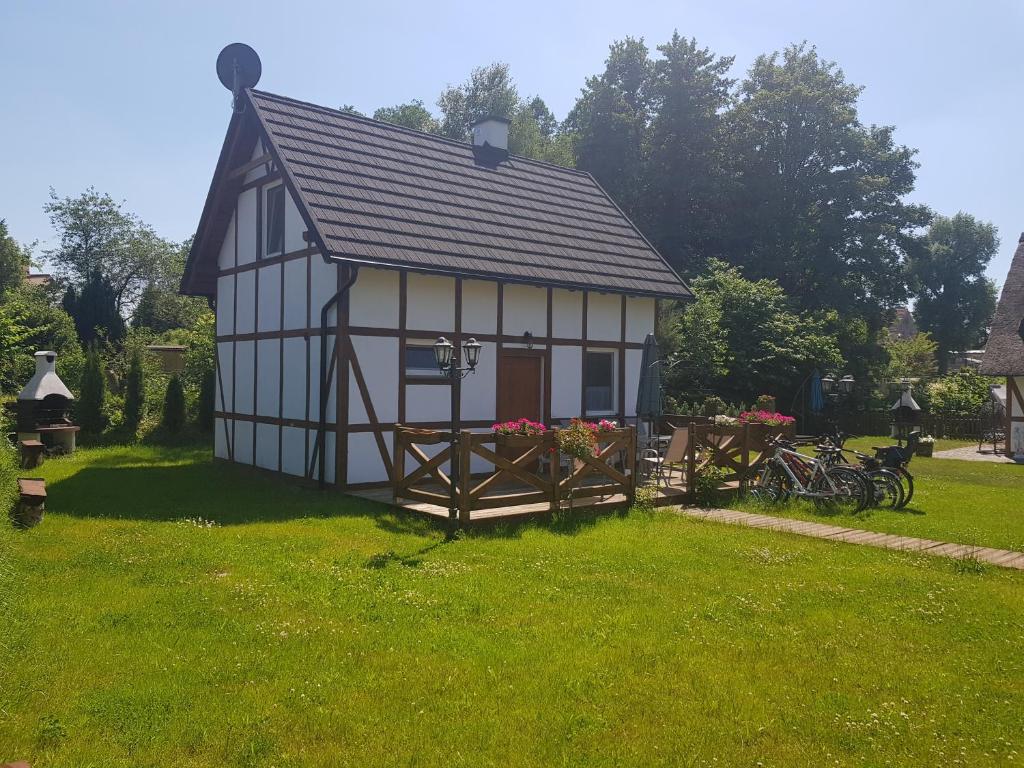 un pequeño edificio blanco y negro en un patio en Chata nad Rzeką, en Lipusz