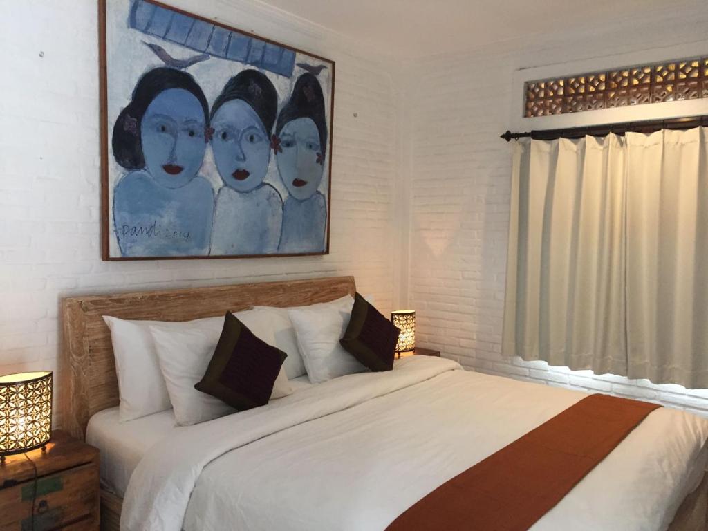 ウブドにあるDepong Houseのベッドルーム1室(ベッド1台付)が備わります。壁には絵画が飾られています。
