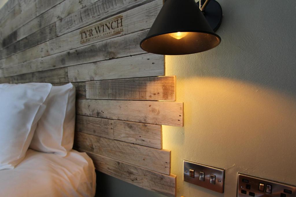 a bedroom with a wooden wall with a bed and a lamp at Tyr Winch in Cardiff