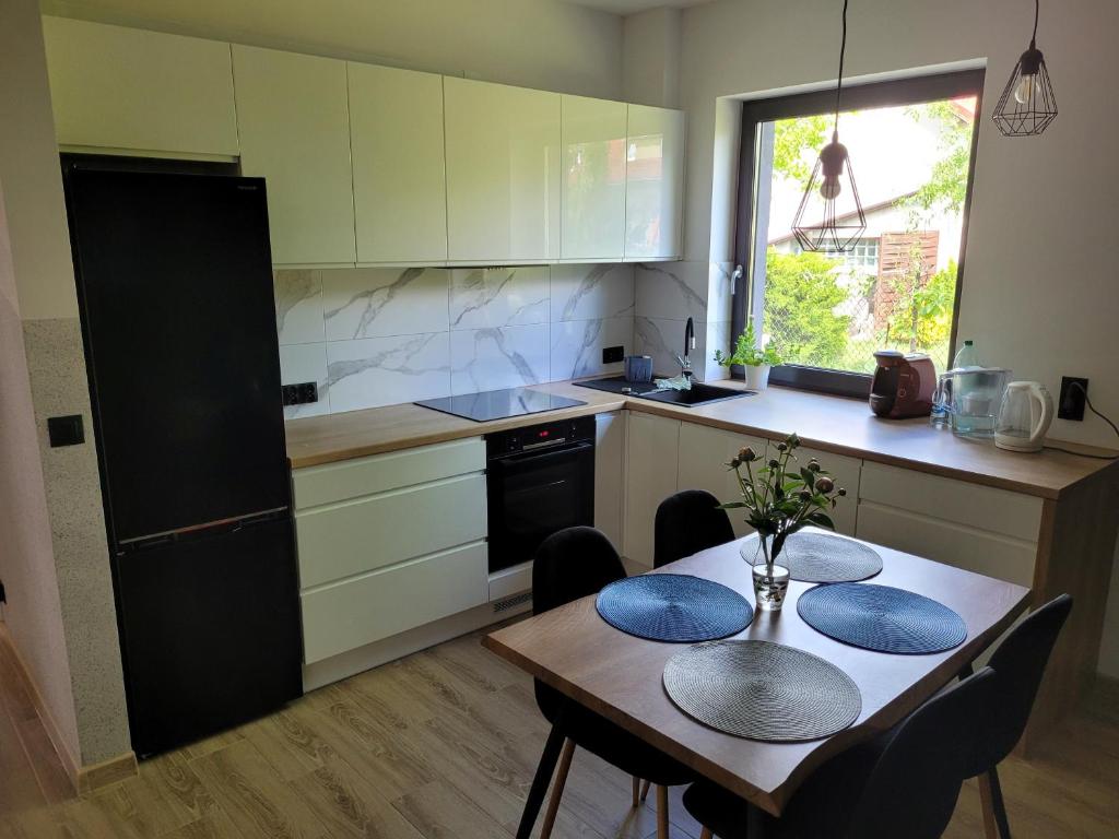 Zbrosławice的住宿－Apartamenty Josef，一间带一张桌子和两把椅子的厨房和一间带白色橱柜的厨房
