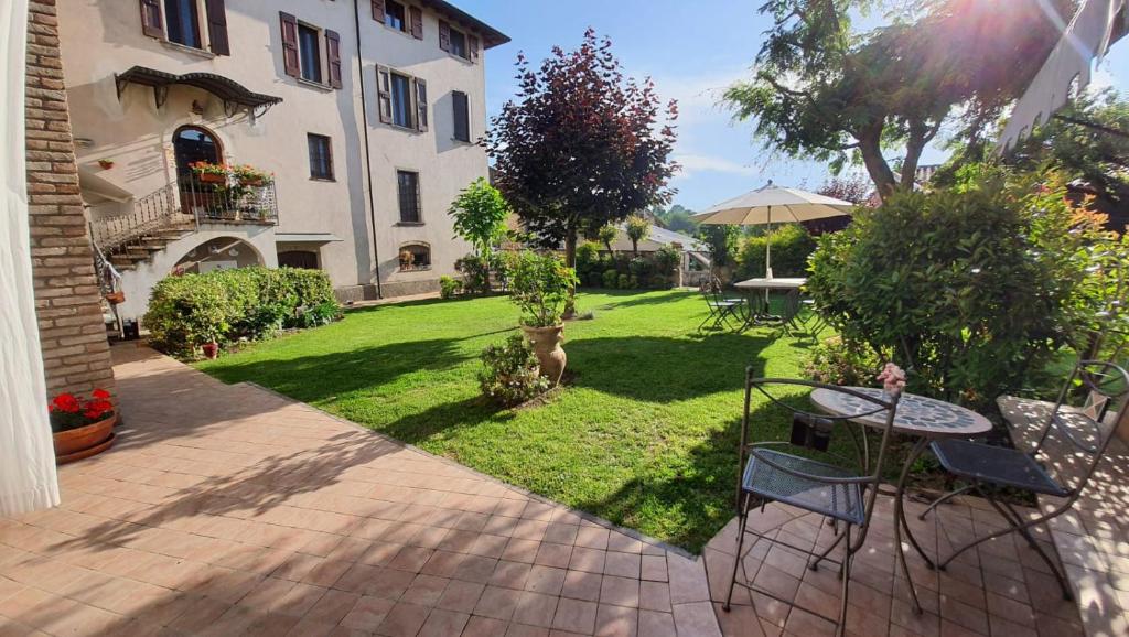 un jardín con mesa y sillas y un edificio en Le Quattro Stagioni B&B and Apartament en Monzambano