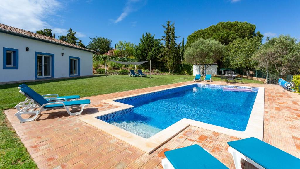 a swimming pool with blue chairs and a house at Luxury Villa With Pool in Vineyard Near the Beach in Porches